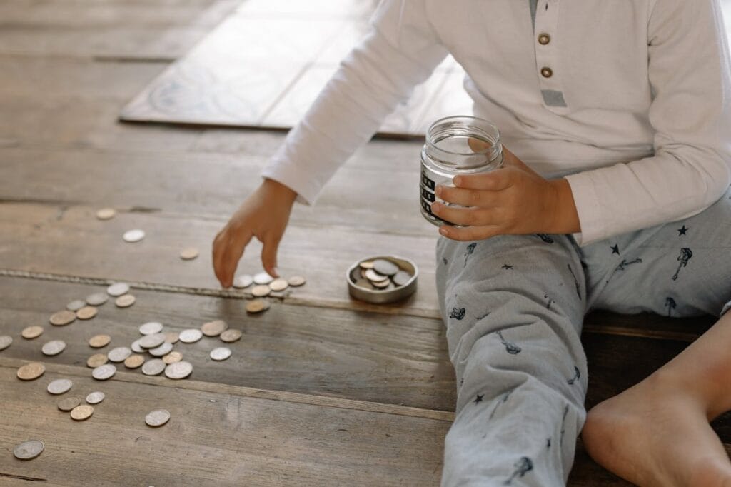 Imagem do post: Educação financeira para os filhos: como ensinar a guardar, investir e empreender | Casal que Soma Educação financeira para os filhos: criança guardando dinheiro no cofrinho