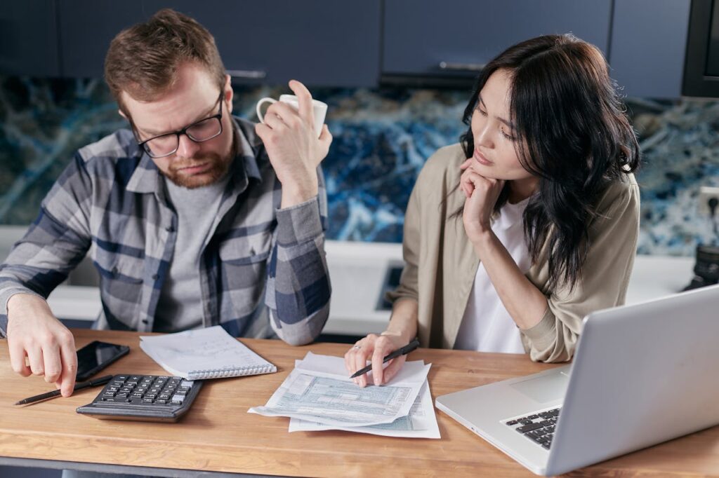 Imagem do post: 15 hábitos que podem destruir a saúde financeira do casal | Casal que Soma Casal sentado em casa conversando sobre finanças com planilha e café na mesa — representando a importância do diálogo para a saúde financeira do casal